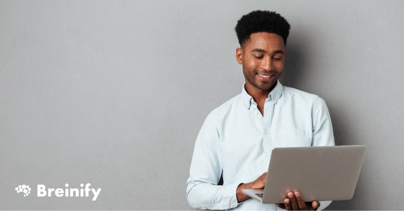 Young black man smiling and holding laptop