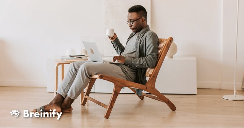 person sitting on a wooden chair with a laptop in their lap